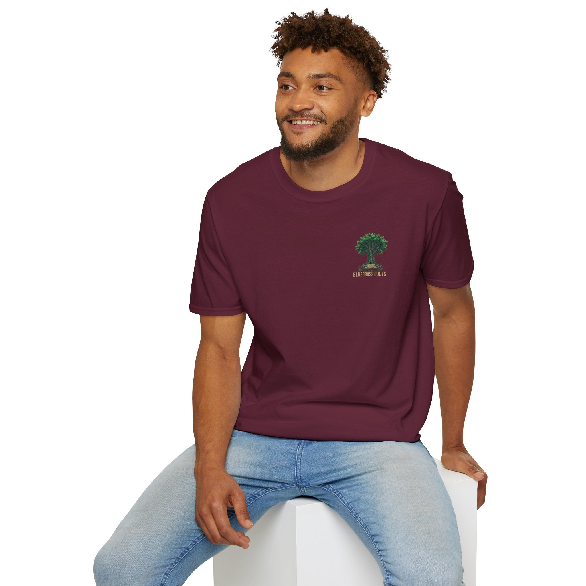 Man wearing a maroon t-shirt with a logo sitting on a white stool against a white background