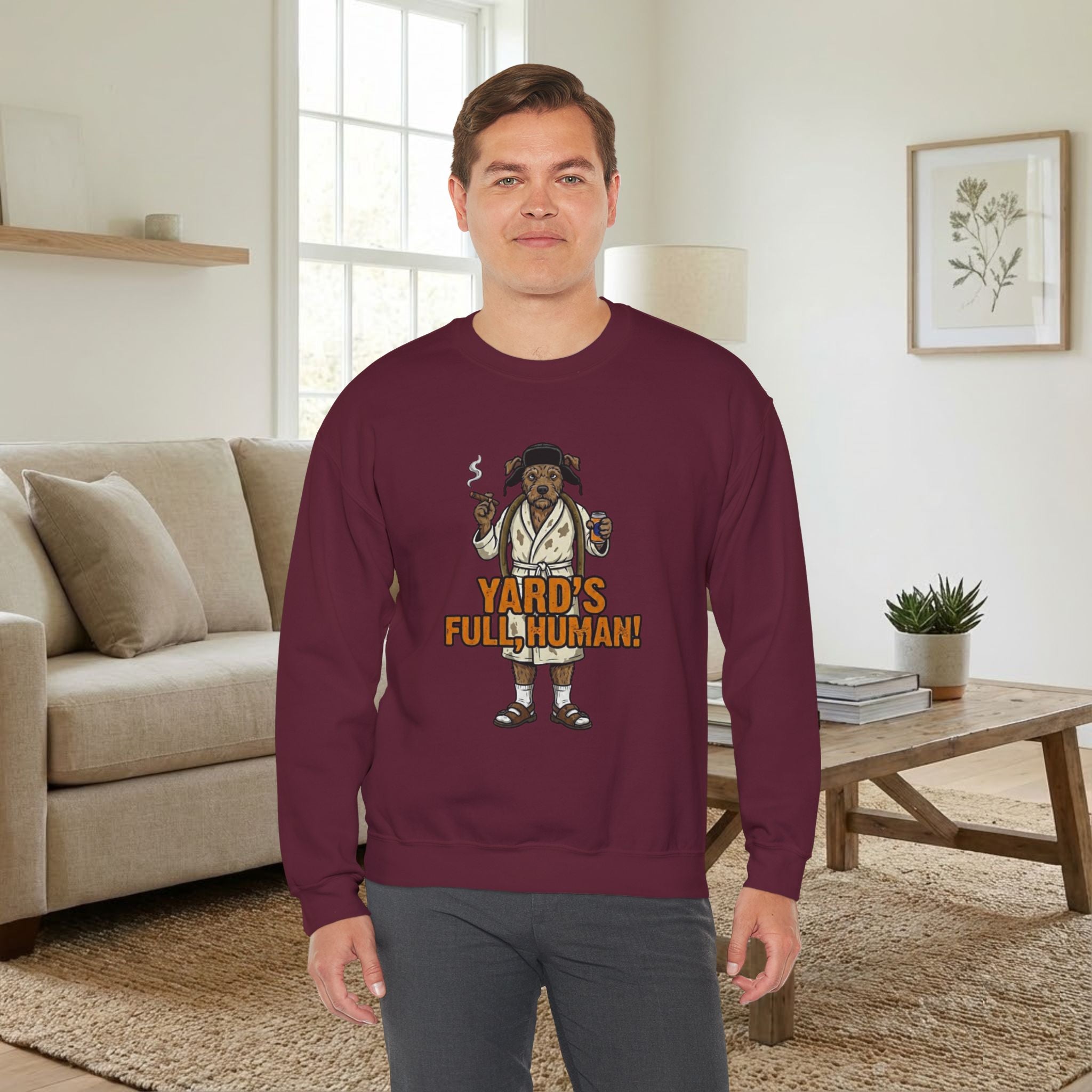 Man wearing a maroon sweatshirt with a graphic design in a living room.
