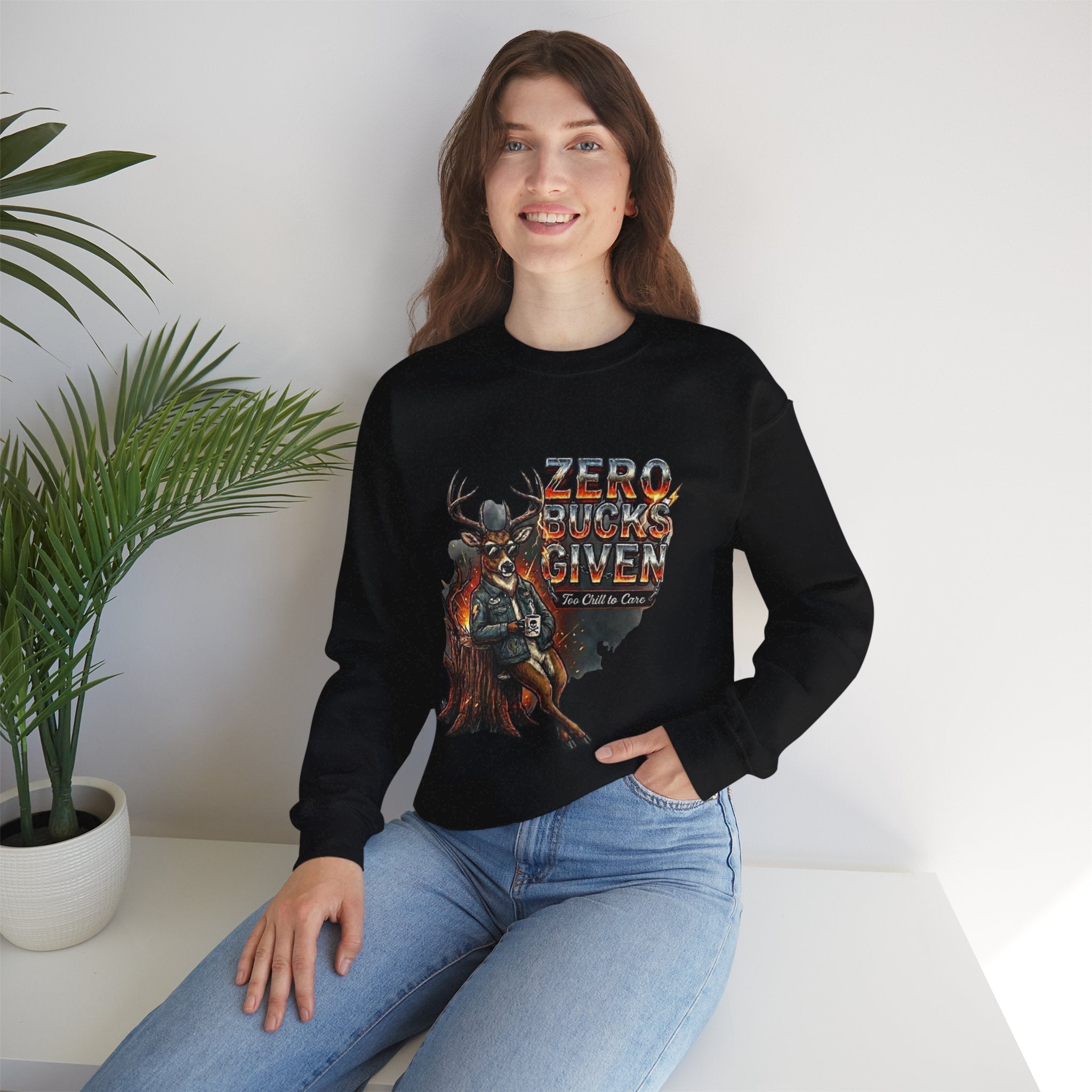 Person wearing a black sweatshirt with 'Zero Bucks Given' graphic design, sitting on a white surface with a plant in the background.