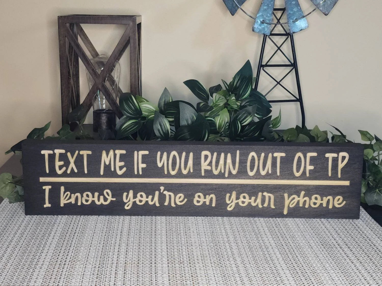 Funny bathroom wall art with a relatable quote styled on a powder room shelf.