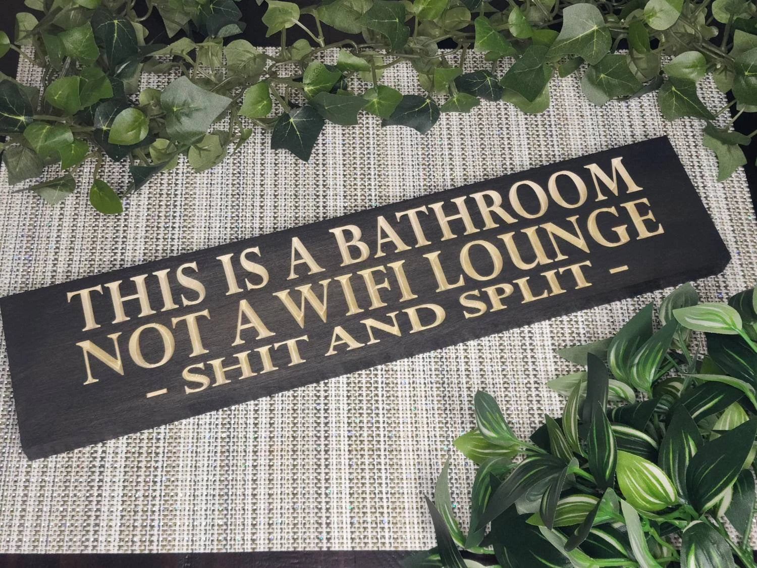 Funny bathroom wall sign that reads "This is a Bathroom, Not a WiFi Lounge – Shit and Split" in a modern guest bathroom.