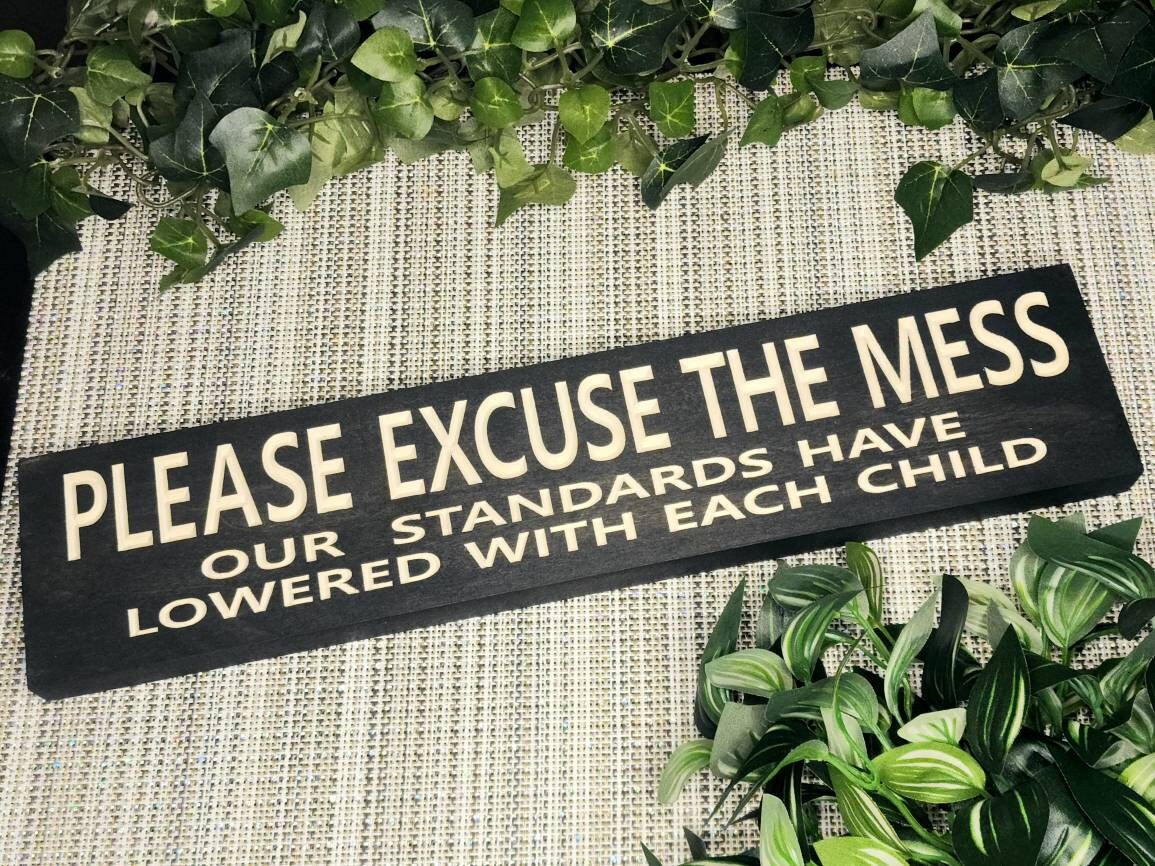 Humorous wooden parenting sign displayed in a cozy family living room.