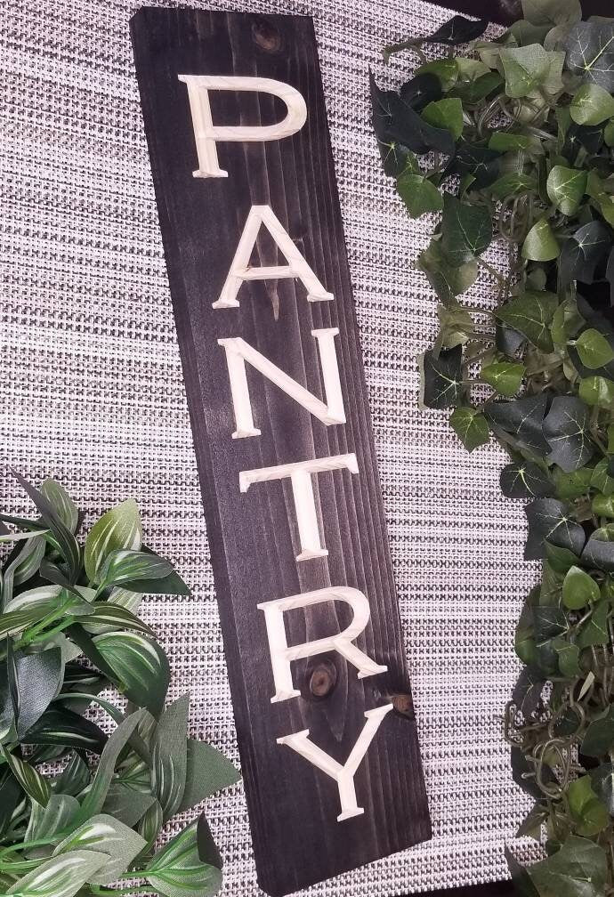 Rustic wooden pantry sign displayed on a pantry door in a farmhouse-style kitchen.