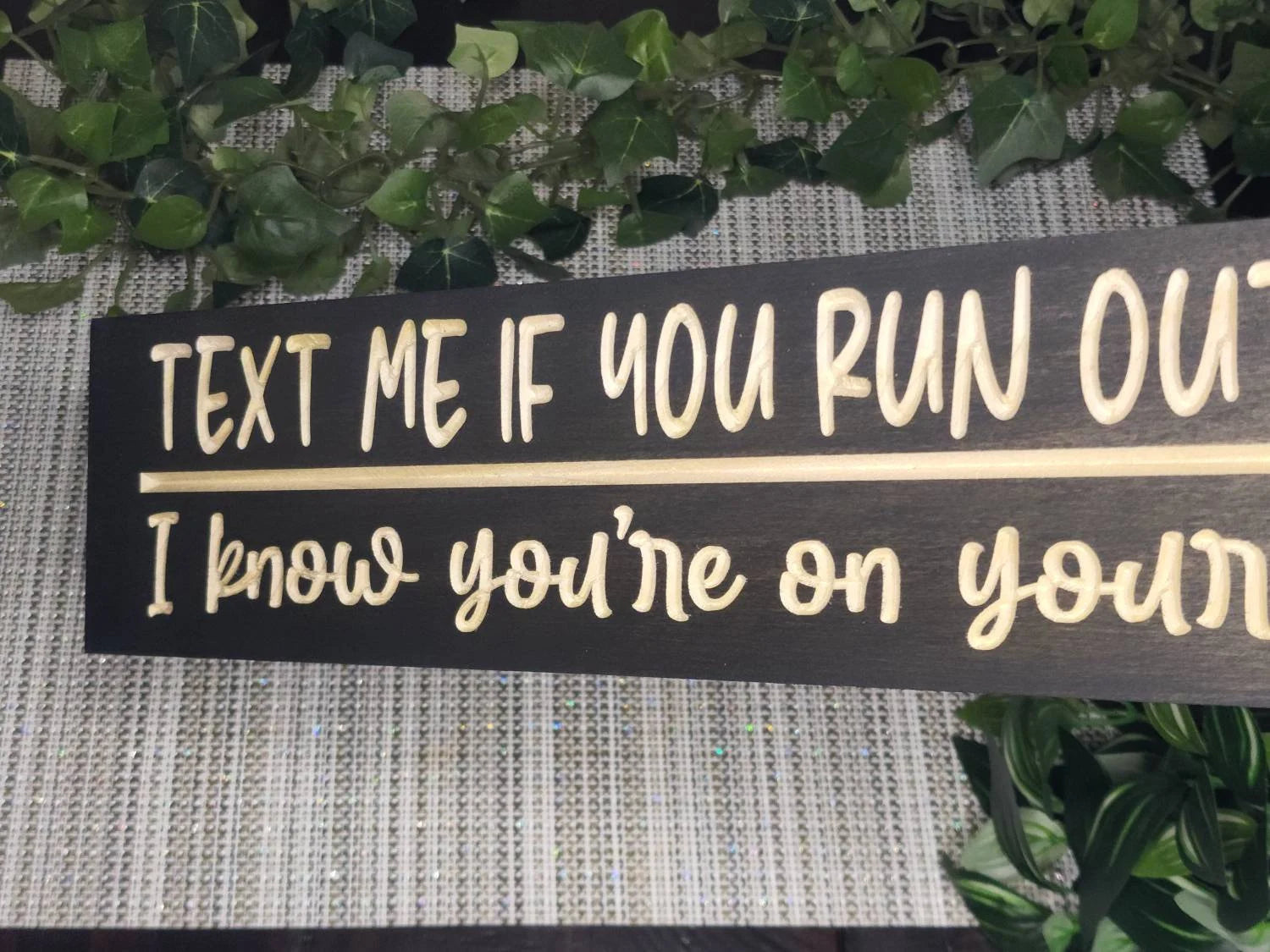 Wooden bathroom decor with humorous TP-related message for guest bathrooms.