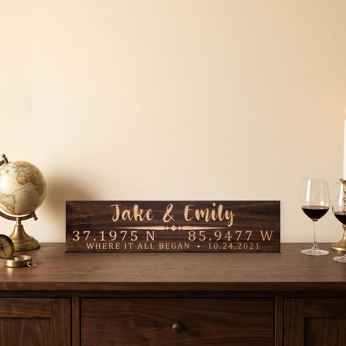 Jake & Emily personalized wood sign standing on a walnut sideboard beside an antique globe and two glasses of red wine