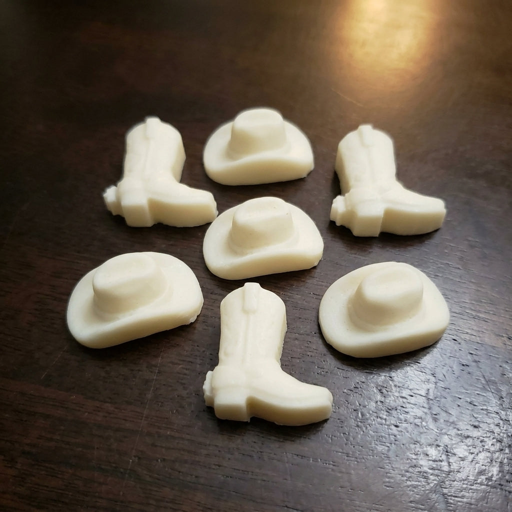 A small group of cream cowboy boot and hat wax melts on a dark wood table
