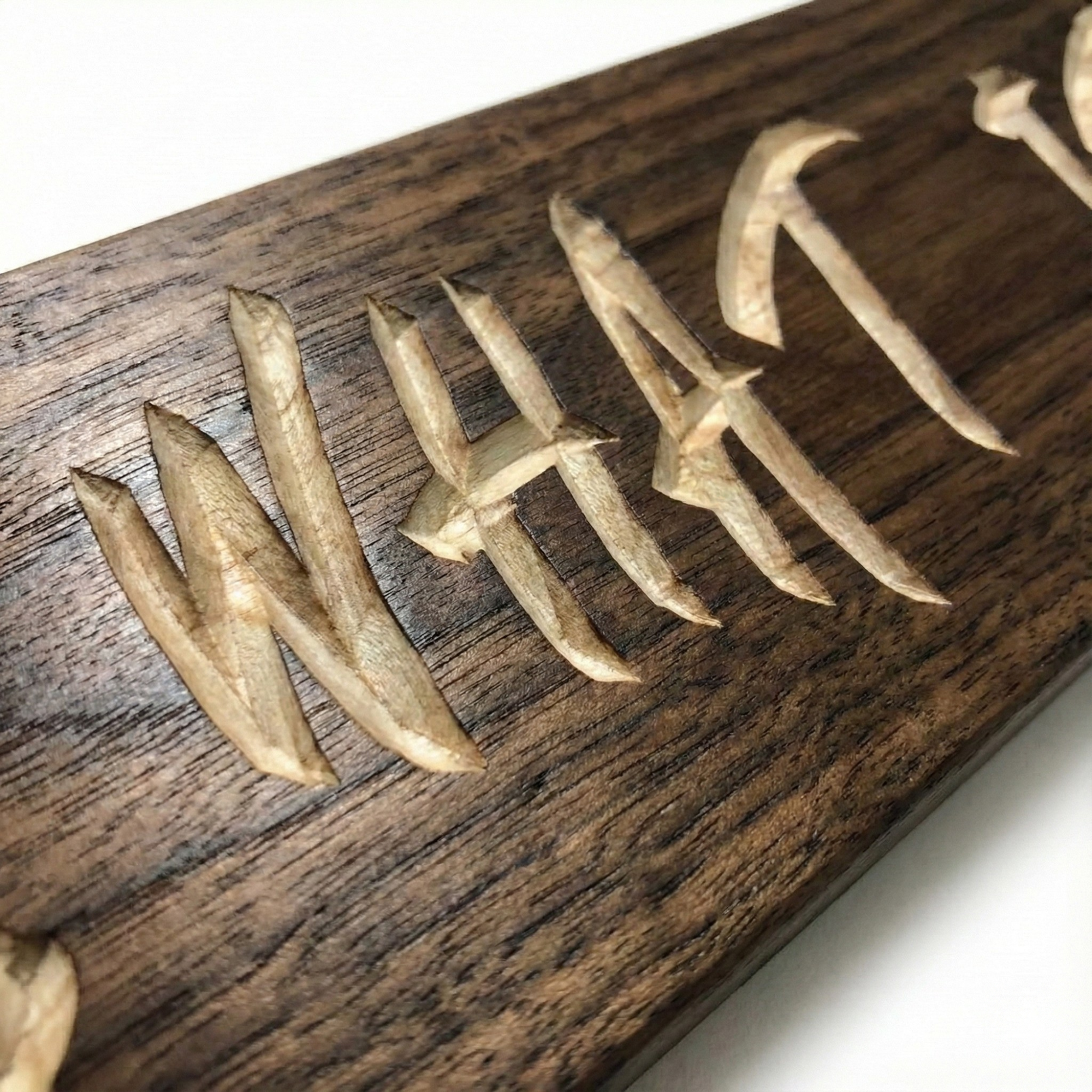 Detailed close-up shot showing the deep V-carve lettering texture and wood grain on the walnut IT IS WHAT IT IS plaque.