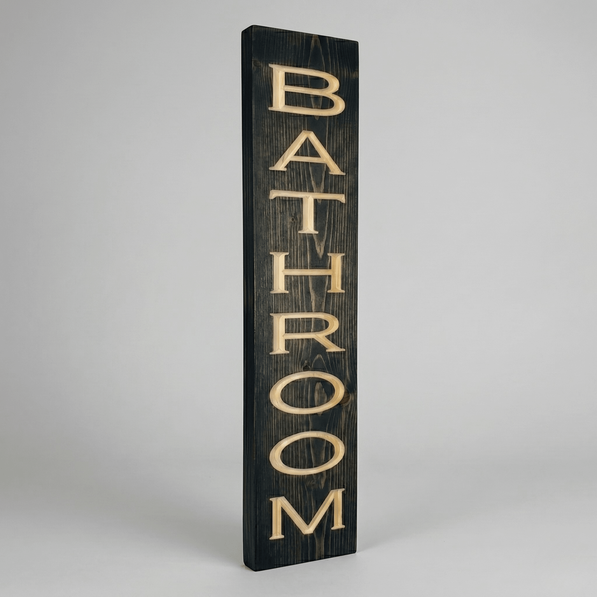 Side angle view of the vertical bathroom wood sign showing dimensional CNC carved letters and solid wood thickness in dark ebony stain finish.