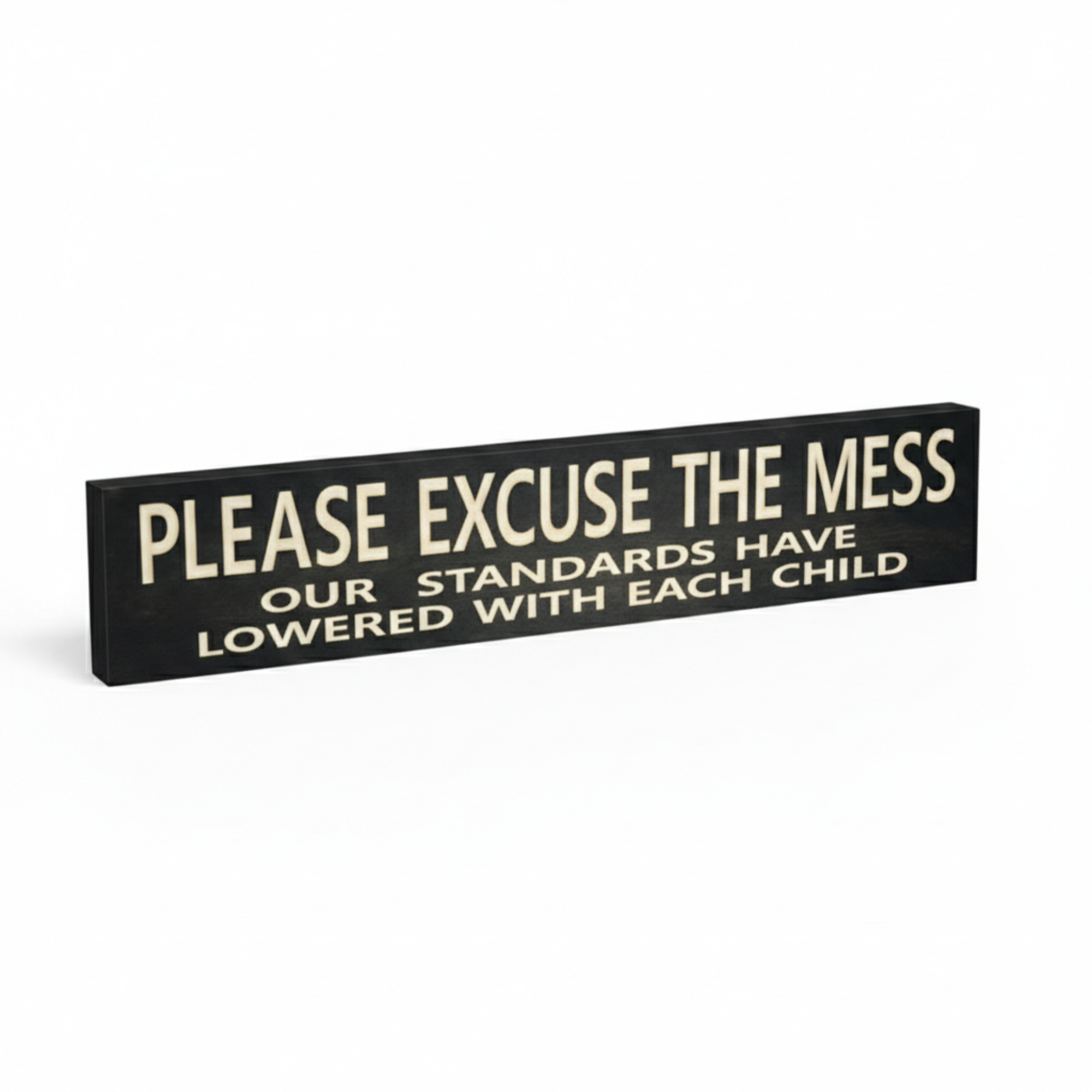 Angled view of a deep-carved wooden home decor sign with the funny parenting quote "Please Excuse the Mess Our Standards Have Lowered With Each Child".