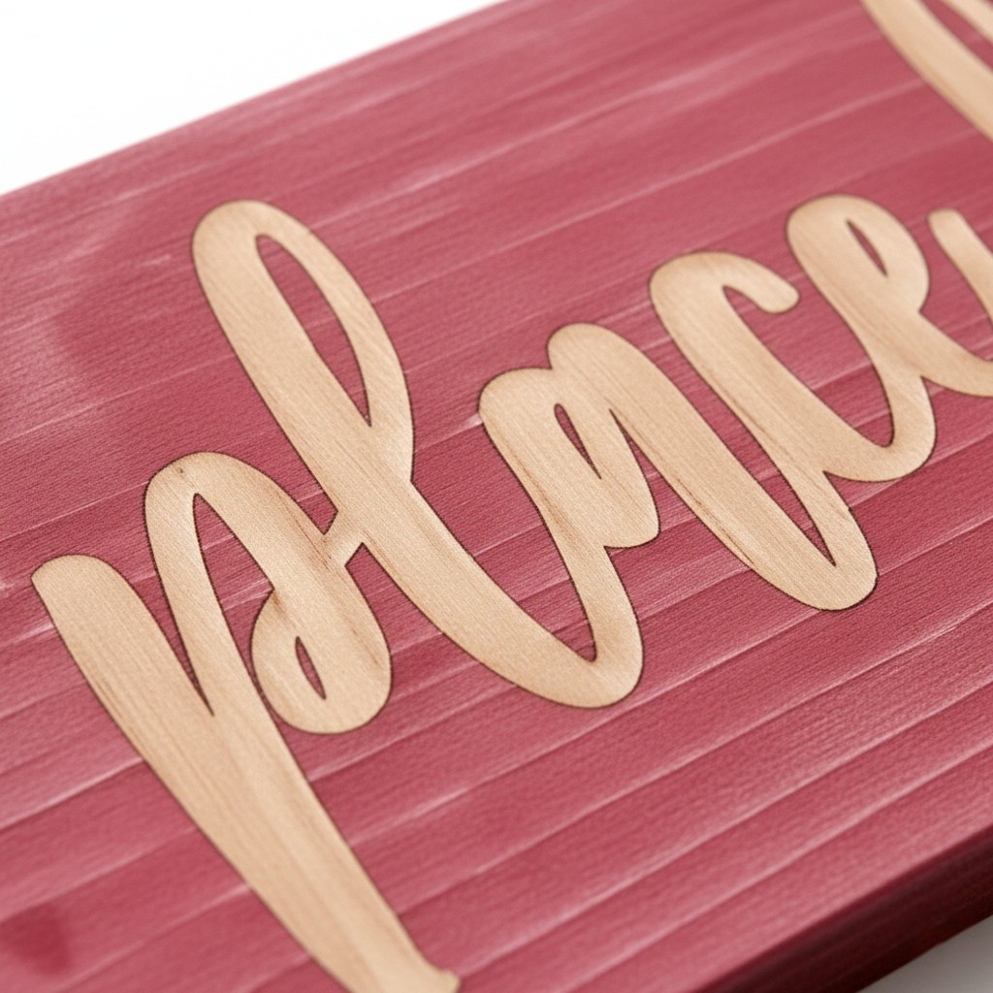 Close-up of deeply carved script lettering on solid wood sign with rustic red finish.