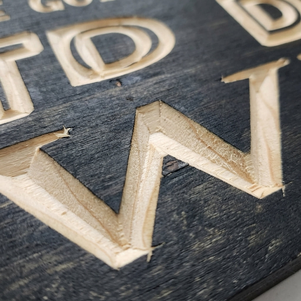A close-up detail shot of the carved letters on the dark wood Coffee and Wine Sign, showing wood grain