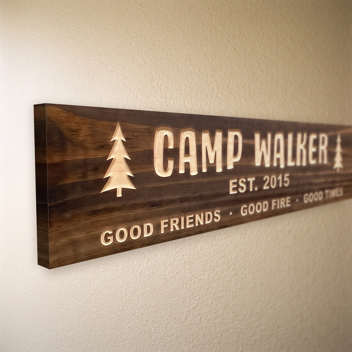 Close-up of the carved letters on the Camp Walker sign, natural pine inside the cuts against the stained grain