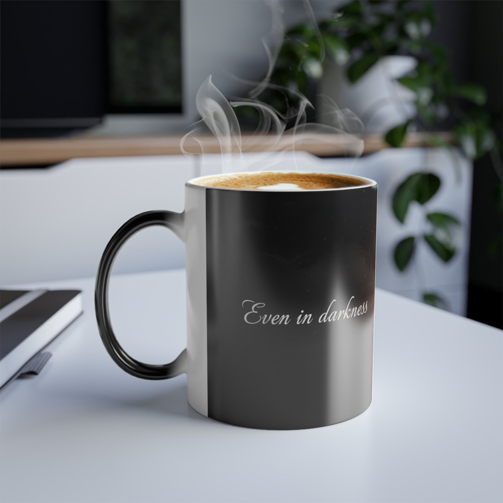 Hot coffee in the “Even in Darkness” mug on a desk with steam rising