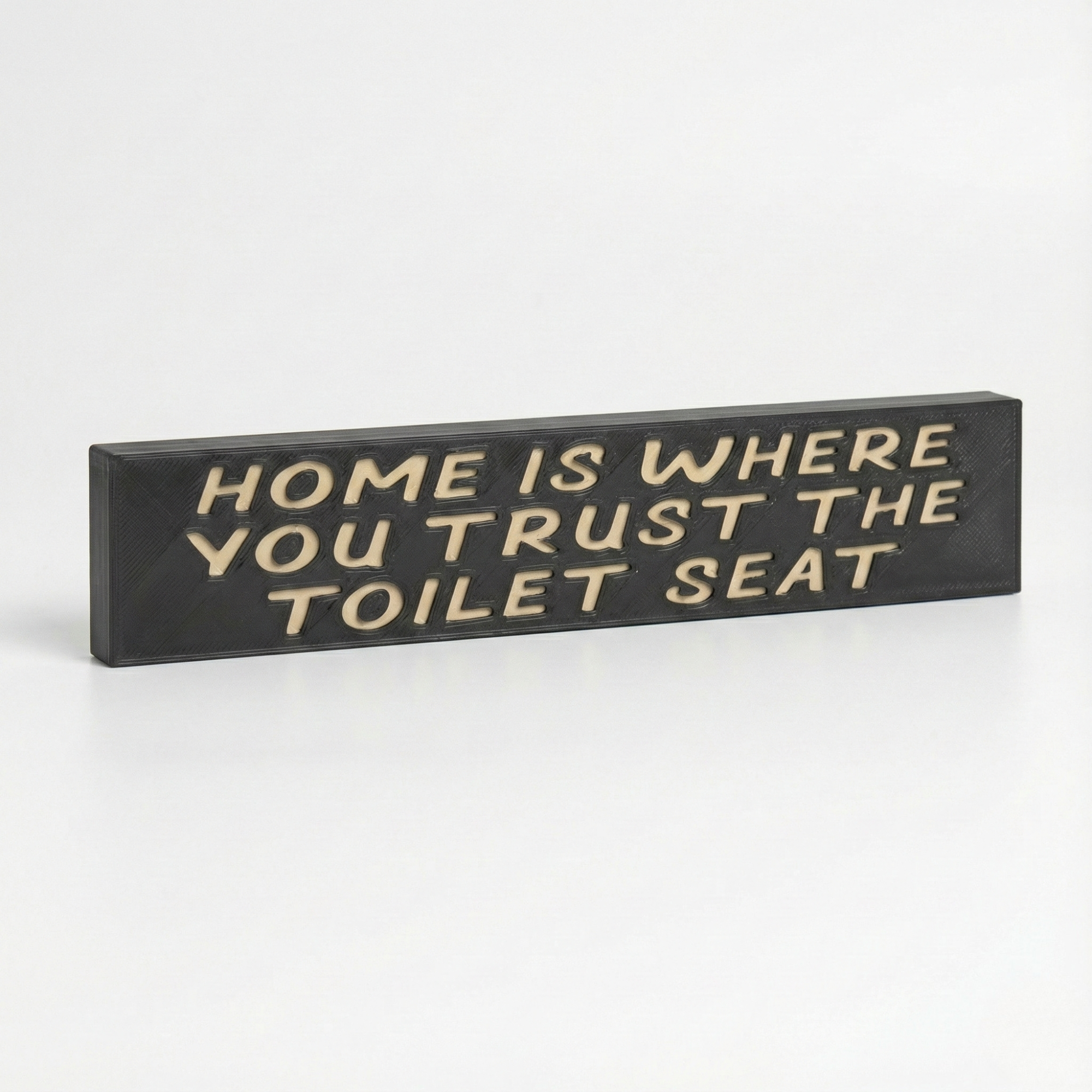 Angled studio view of a rustic wood sign reading "Home Is Where You Trust The Toilet Seat" featuring deep V-carved lettering and dark stain.