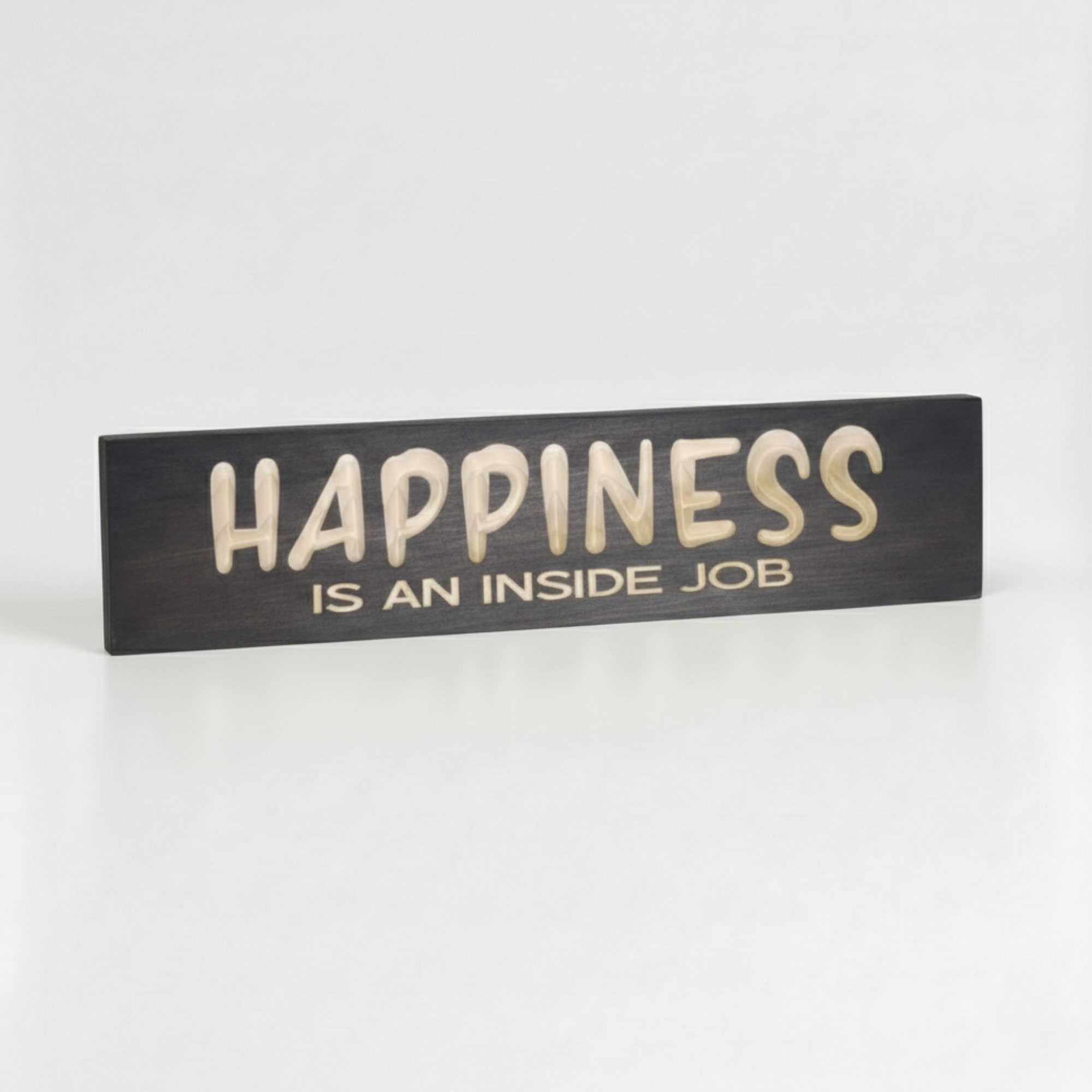 Close-up angled shot of the Happiness Is An Inside Job sign highlighting the 3D depth of the CNC V-carve lettering and solid wood texture.