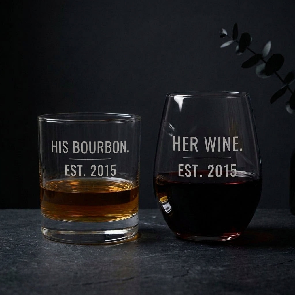 His Bourbon Her Wine engraved glass set on dark slate with the etching lit for contrast