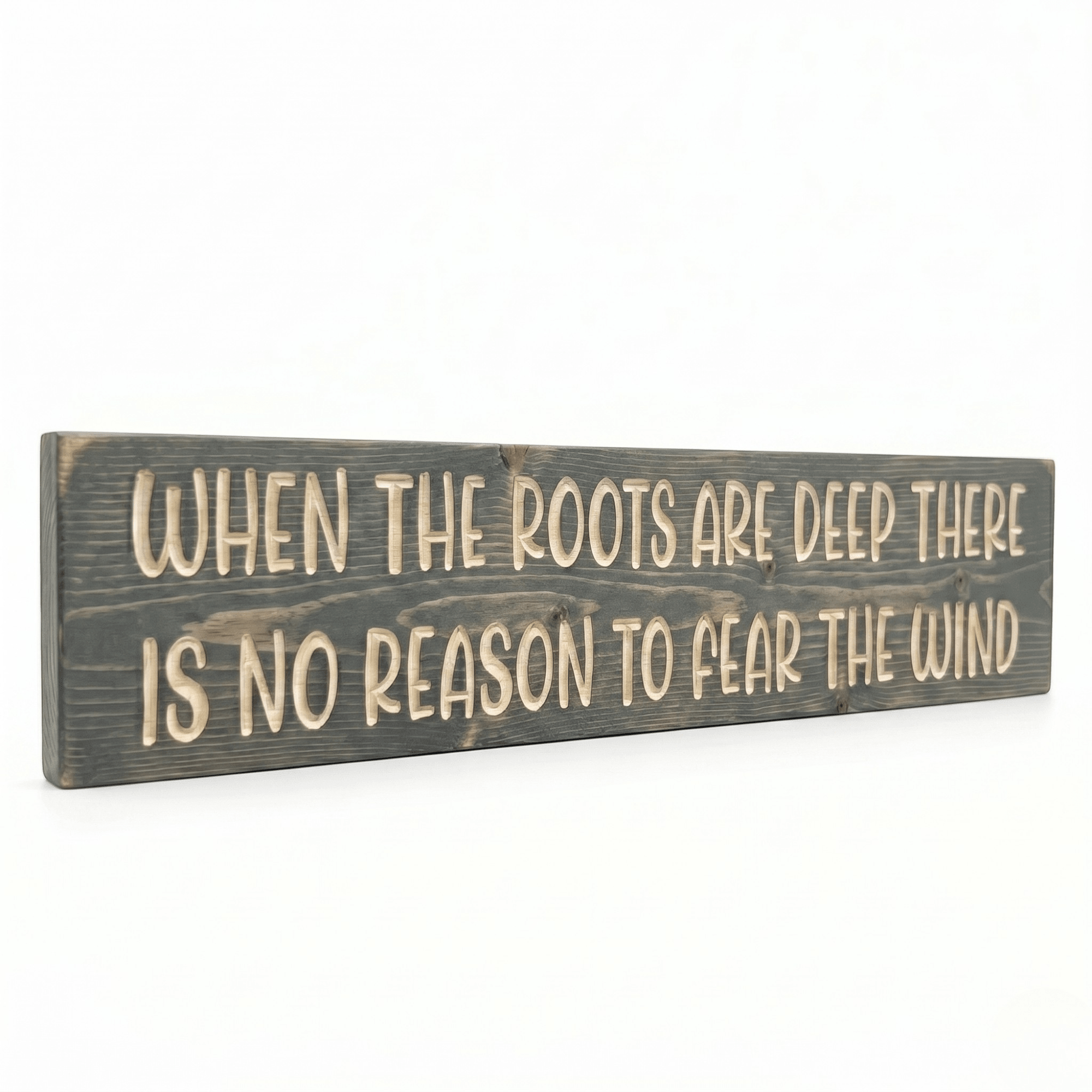Angled view of solid pine When the Roots Are Deep wood sign showing dimensional CNC-carved lettering and weathered gray stain finish