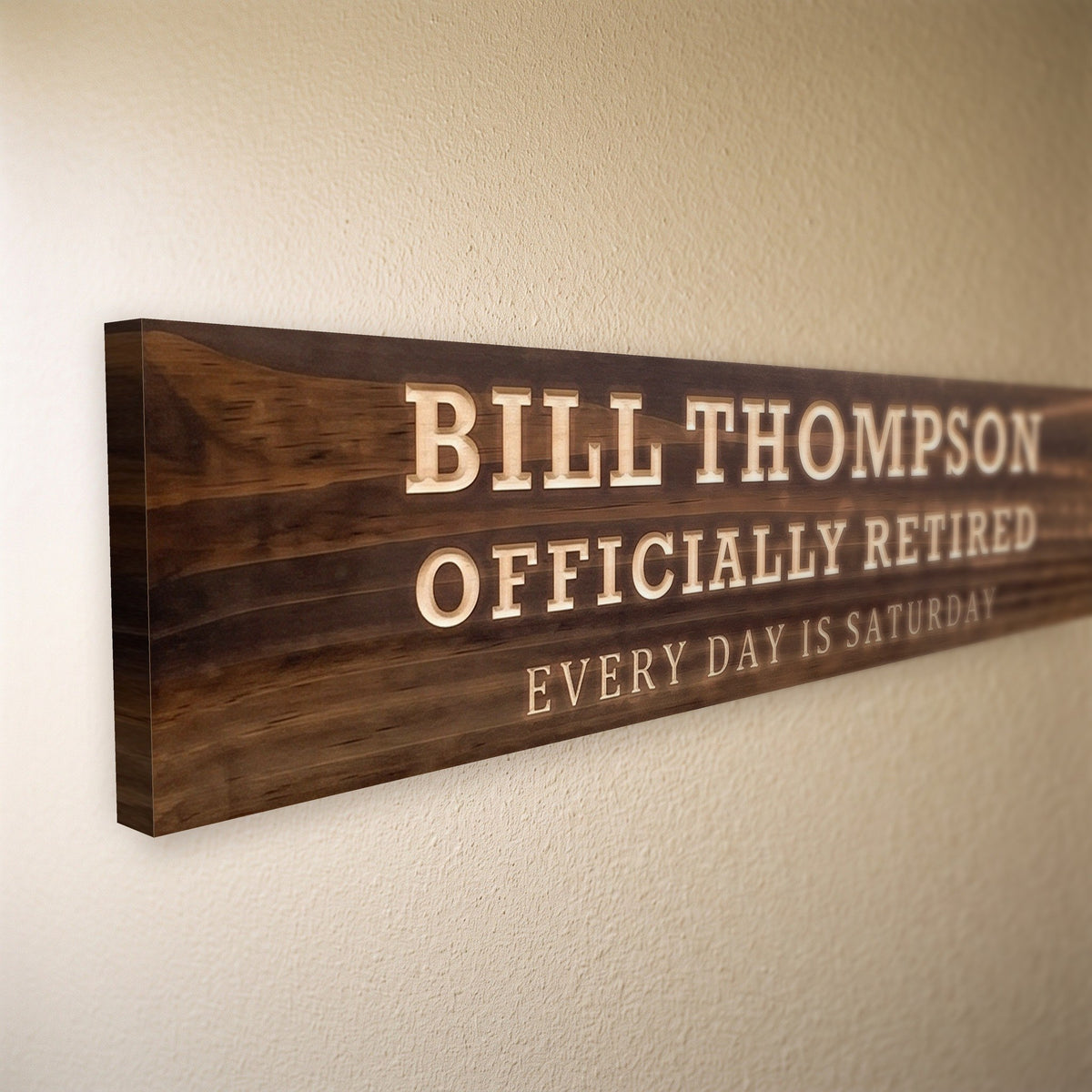 Close-up of the carved letters on the Bill Thompson sign, natural pine inside the cuts against the stained grain