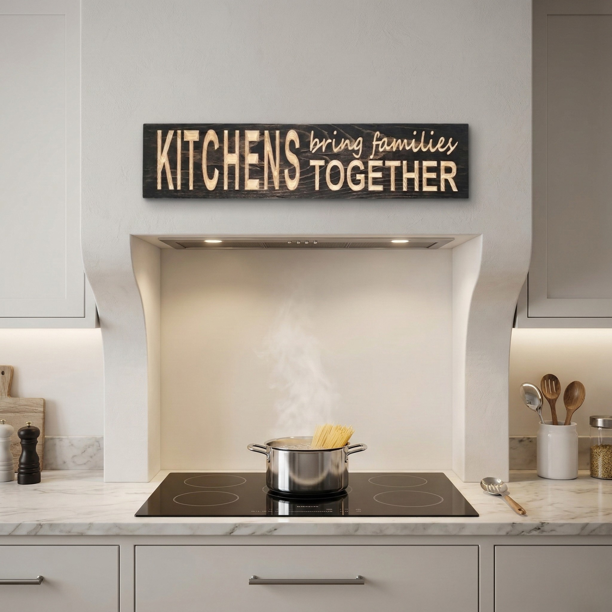 A large "KITCHENS bring families TOGETHER" wooden sign mounted on a white wall above a modern induction stove in a bright kitchen.