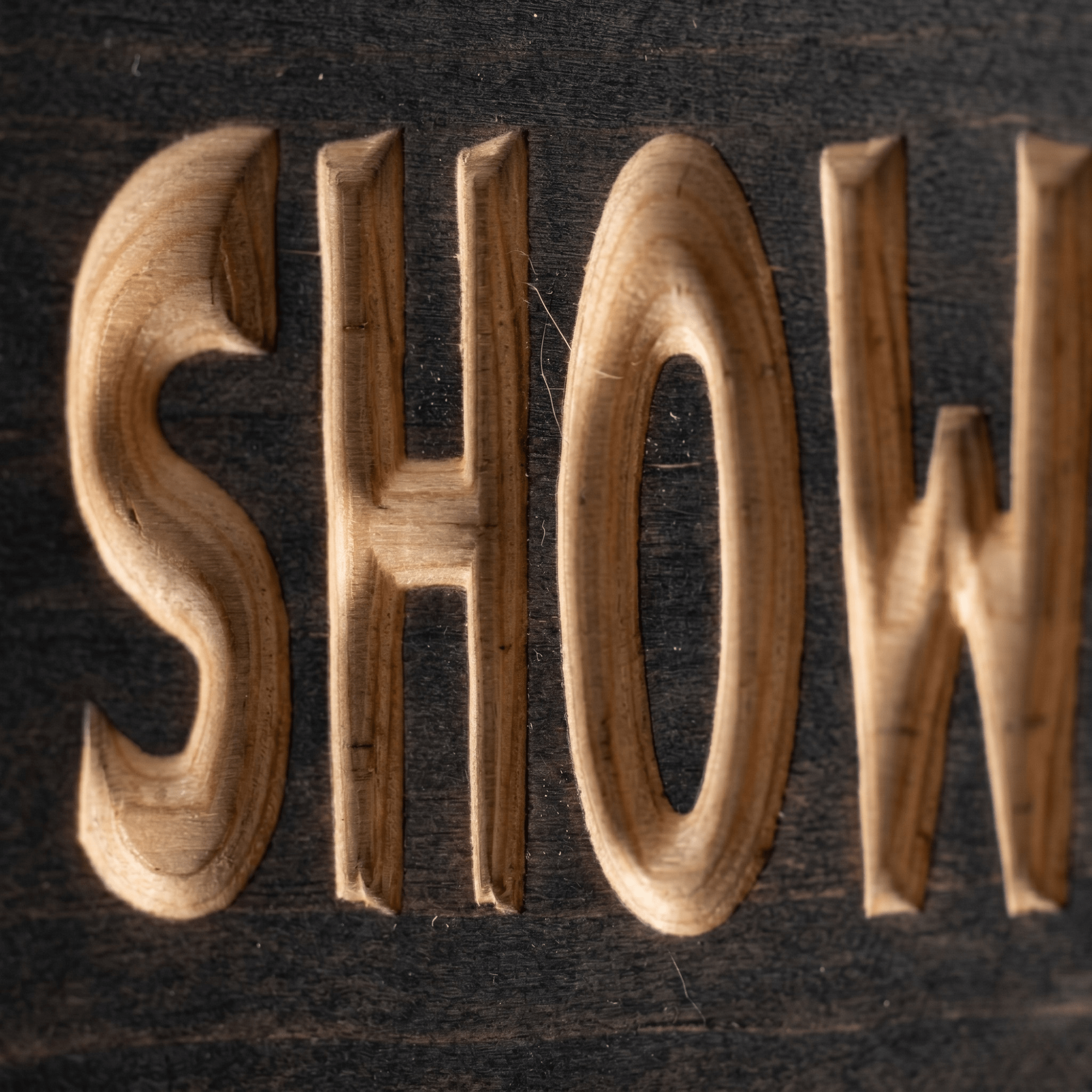 Macro close-up of CNC-carved SHOWER letters revealing natural pine beneath the dark stain.