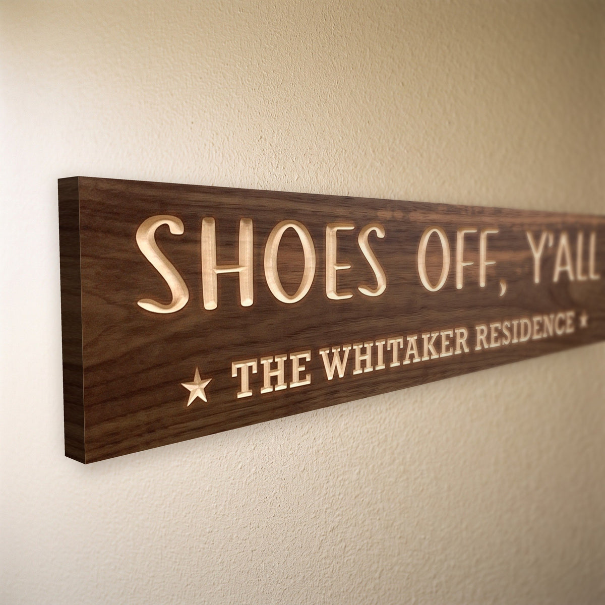 Close-up of the carved letters on the Shoes Off, Y'all sign, natural pine inside the cuts against the stained grain