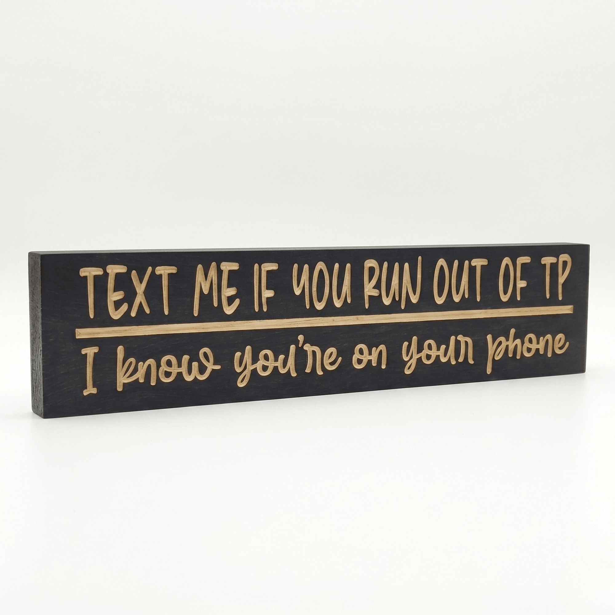Angled view of the Text Me If You Run Out of TP funny bathroom sign showing dimensional CNC-carved letters and rich Ebony stain on solid Pine