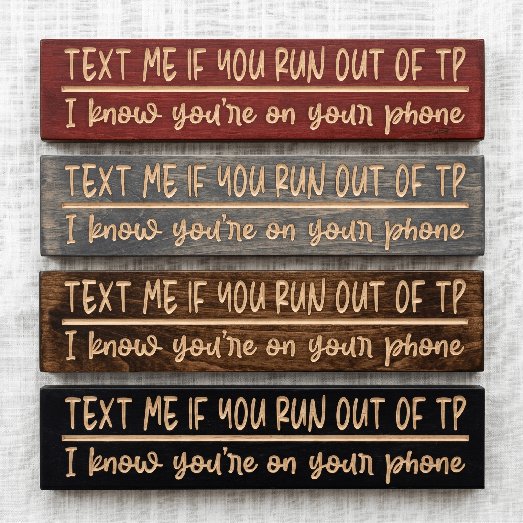 Four Text Me If You Run Out of TP CNC-carved bathroom signs stacked to show stain options including Cabernet, Carbon Gray, Dark Walnut, and Ebony