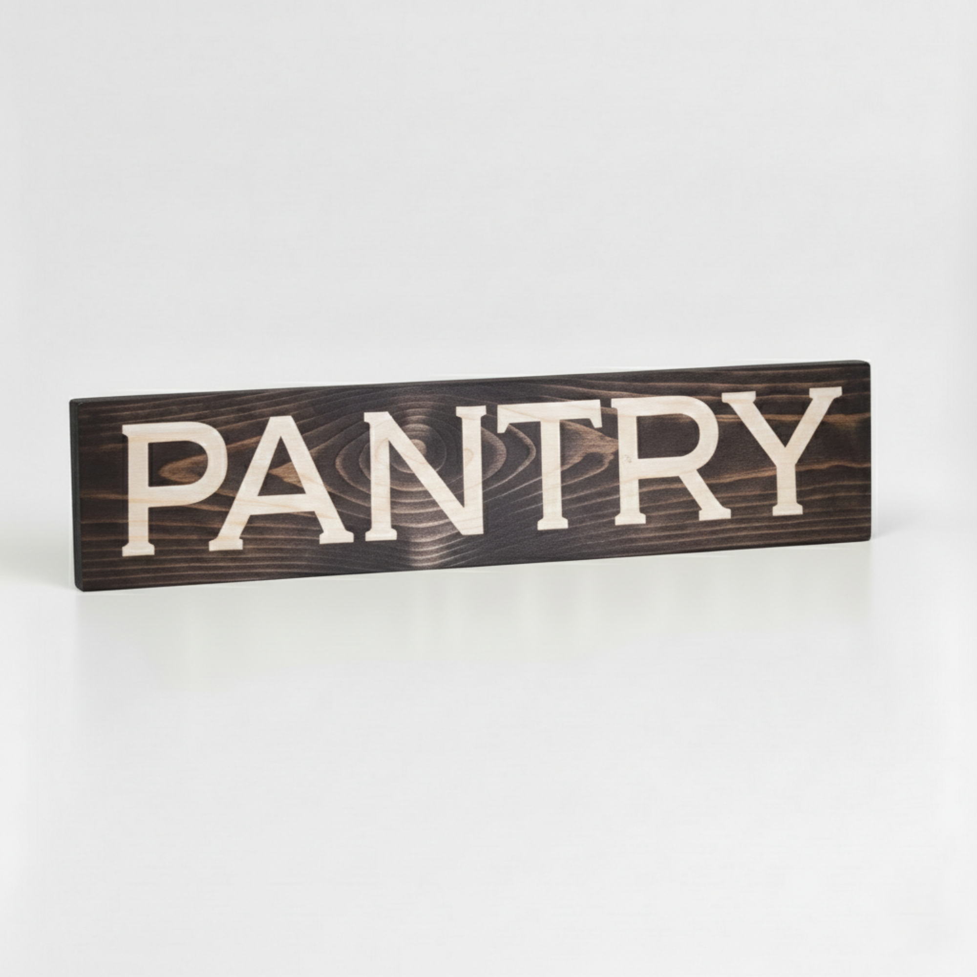 Angled view of a handcrafted wooden PANTRY sign showing the high-contrast natural wood grain in the carved letters.