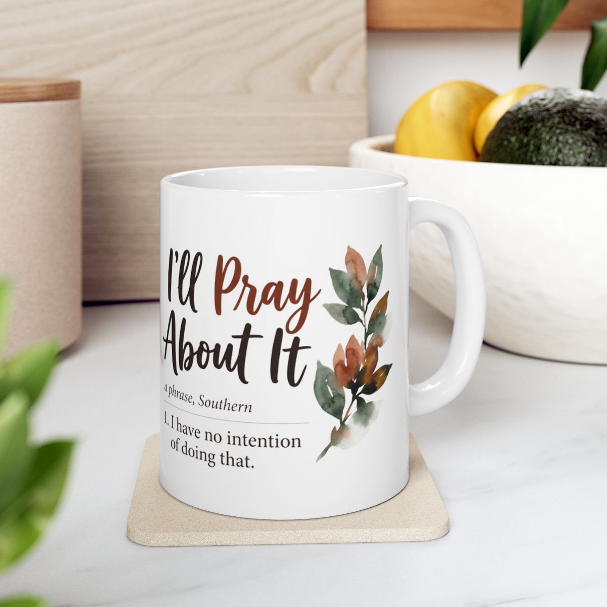 A Sarcastic Coffee Mug resting on a light-colored coaster in a kitchen setting with fruit and cutting boards visible