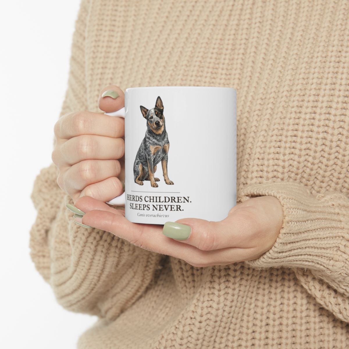 A person in a beige sweater holds the Dog Mom Mug, showing the cattle dog design and text clearly against their clothing