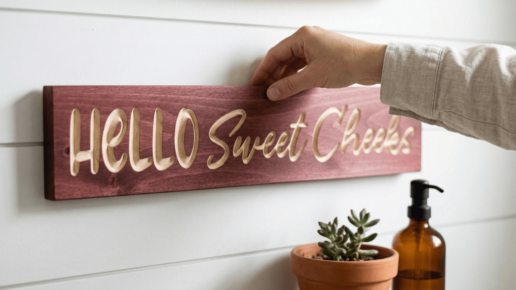 Wide view of a bright, modern bathroom with the 'HELLO Sweet Cheeks' funny wooden sign hanging over the toilet — BluegrassGifts.com