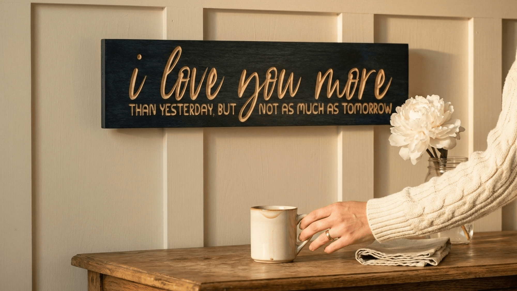 Romantic love quote wooden sign hanging above white farmhouse bed in cozy bedroom with shiplap walls and vintage quilt