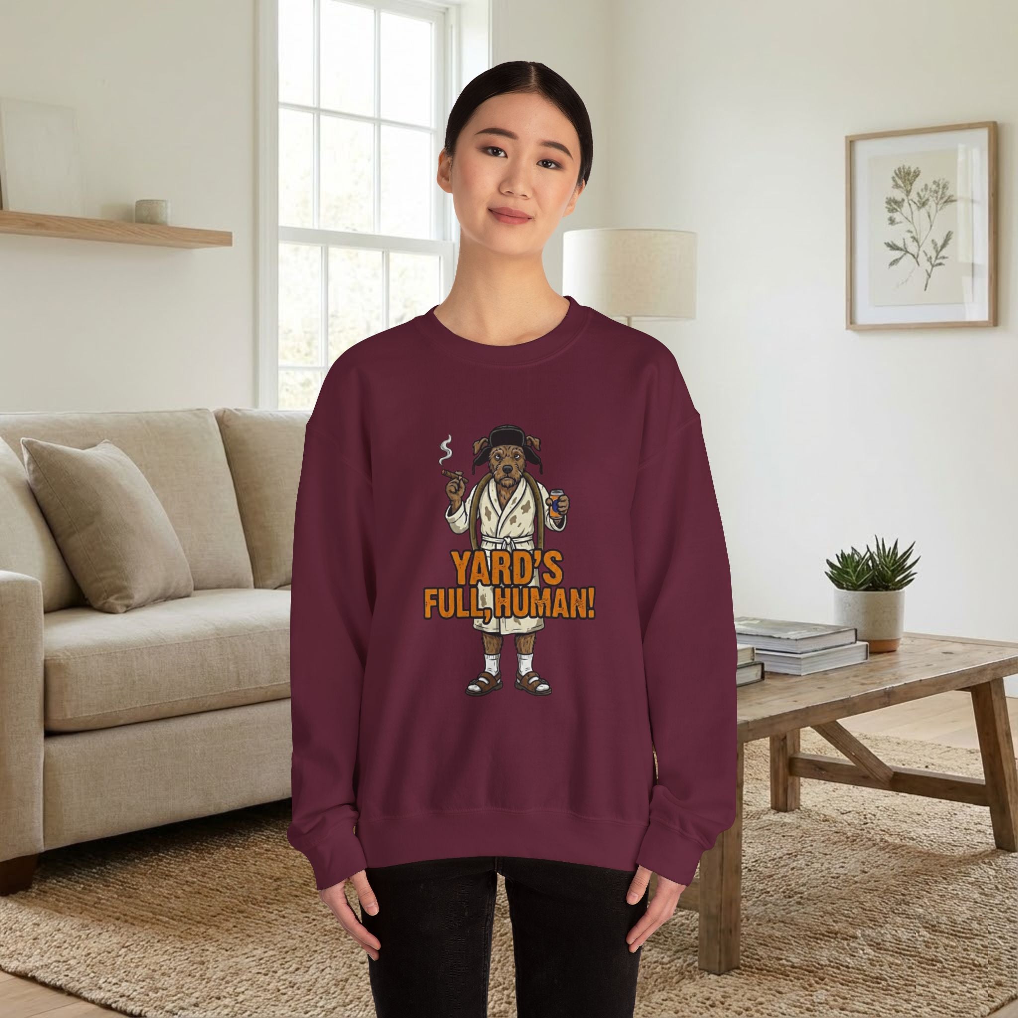 Person wearing a maroon sweatshirt with a graphic design in a living room.