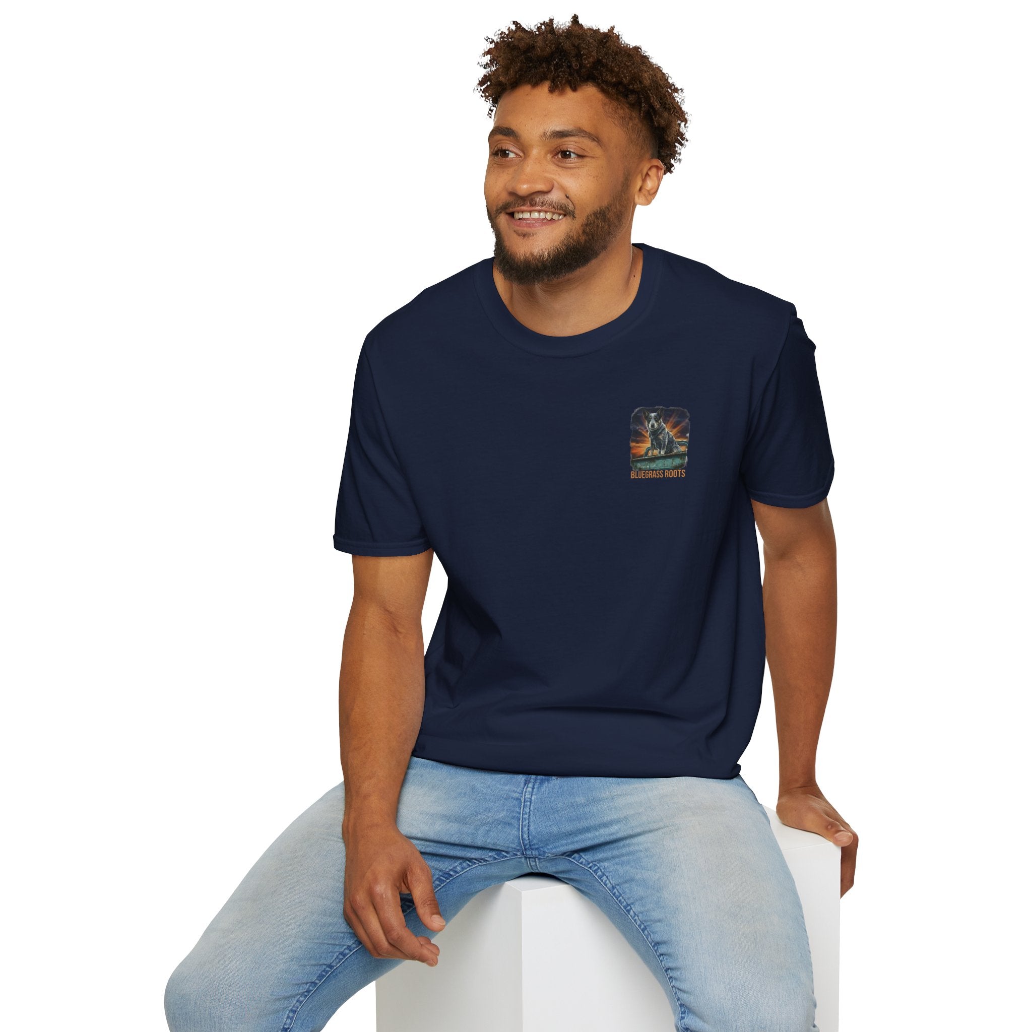 Man wearing a navy blue t-shirt with a logo sitting on a white stool against a white background