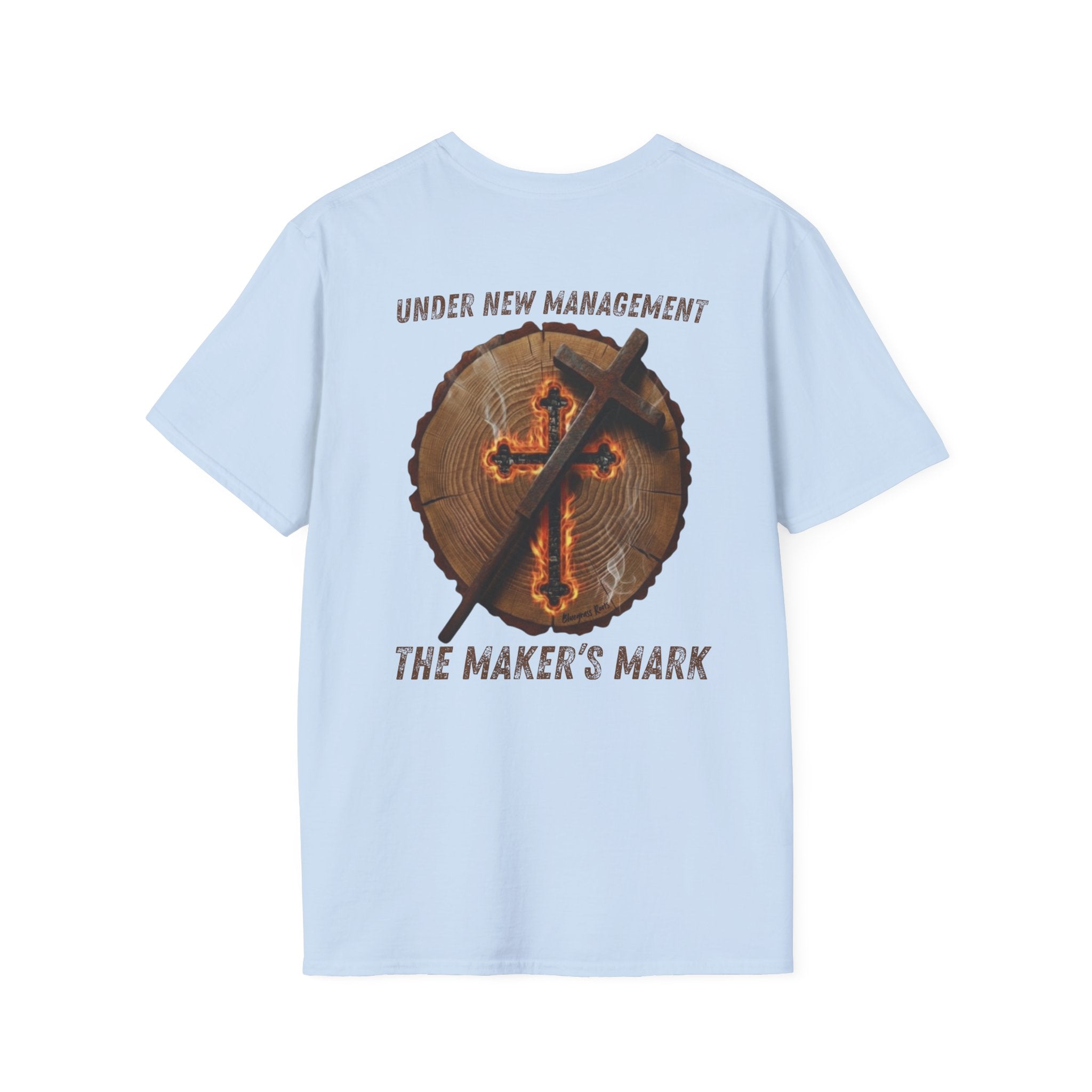 Light blue premium t-shirt featuring a high-resolution back-print of a natural timber log round with detailed growth rings. Centered on the wood grain is a glowing, ember-lit cross that appears deeply scorched into the surface, emitting light wisps of white smoke. A rustic, weathered metal branding iron in the shape of a cross leans diagonally against the wood.

The arched text above the graphic reads "UNDER NEW MANAGEMENT" in a distressed orange, vintage-style font. Below the timber round, the bold text re