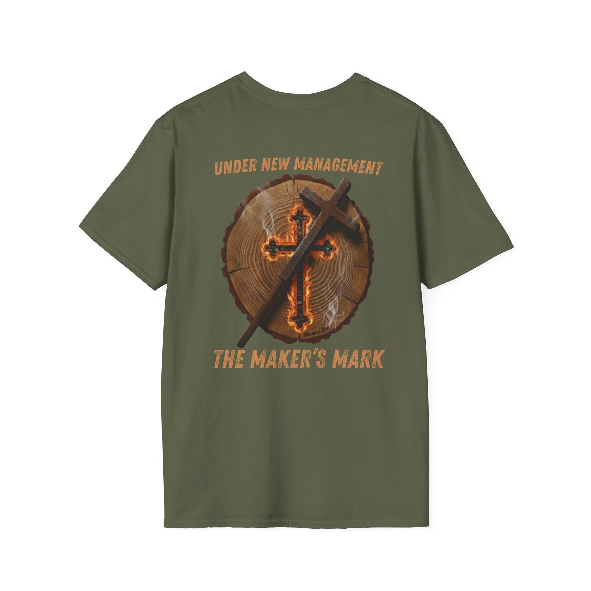 Green premium t-shirt featuring a high-resolution back-print of a natural timber log round with detailed growth rings. Centered on the wood grain is a glowing, ember-lit cross that appears deeply scorched into the surface, emitting light wisps of white smoke. A rustic, weathered metal branding iron in the shape of a cross leans diagonally against the wood.

The arched text above the graphic reads "UNDER NEW MANAGEMENT" in a distressed orange, vintage-style font. Below the timber round, the bold text reads "
