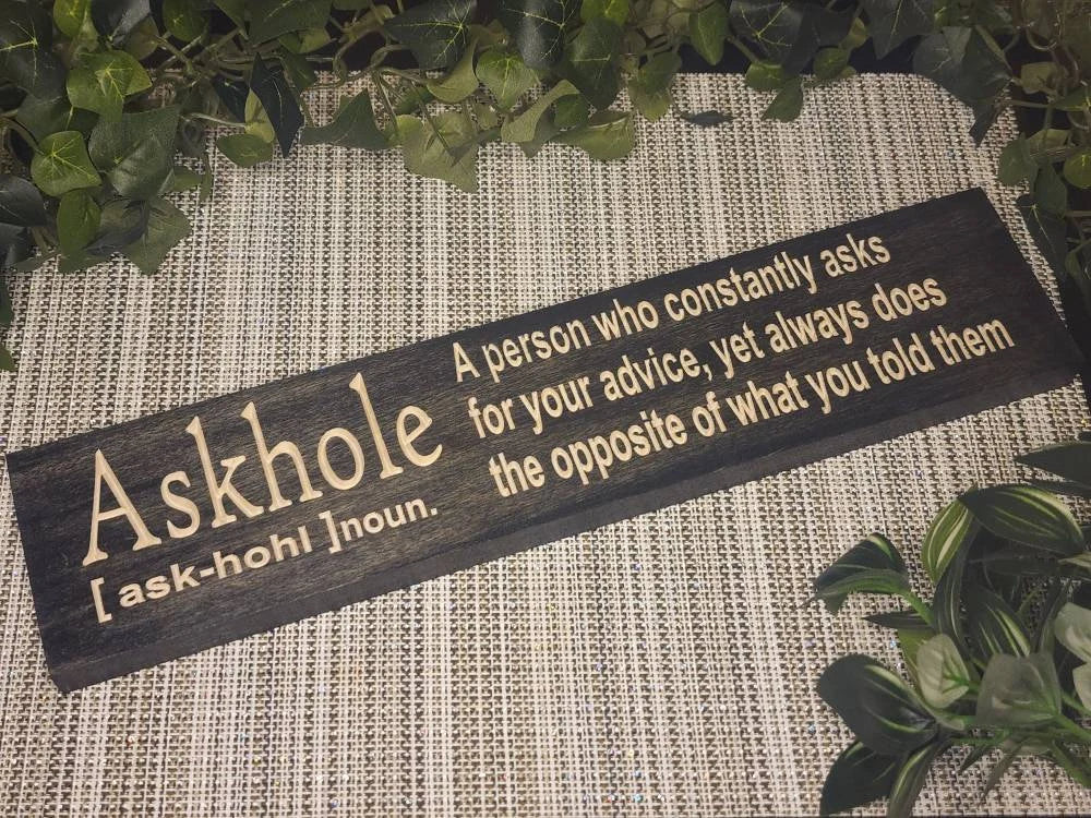 ASKHOLE funny definition wooden sign displayed on an office desk.
