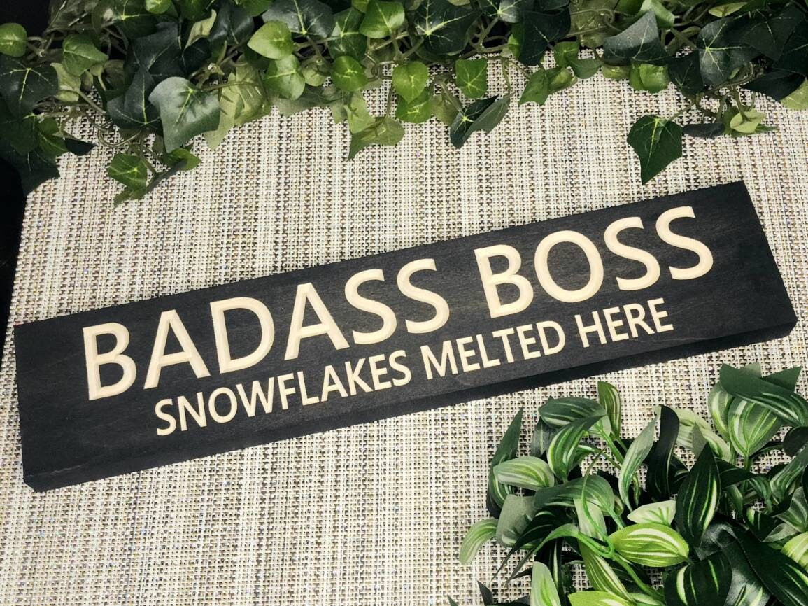 "Badass Boss – Snowflakes Melted Here" wooden sign displayed in a modern office.
