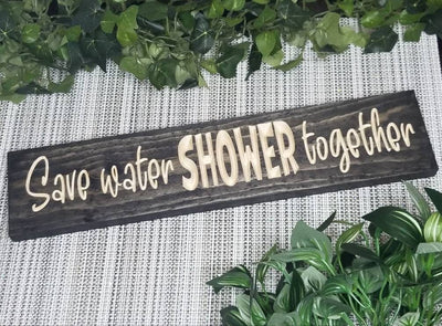 Funny "Save Water, Shower Together" bathroom sign displayed above a bathtub.
