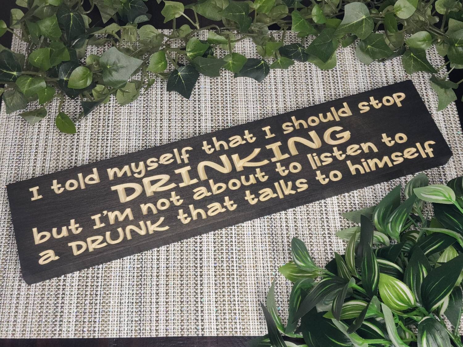 Funny drinking quote sign displayed in a rustic home bar setting.
