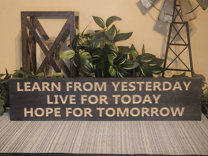 Inspirational wooden sign hanging in a modern home office for daily motivation.
