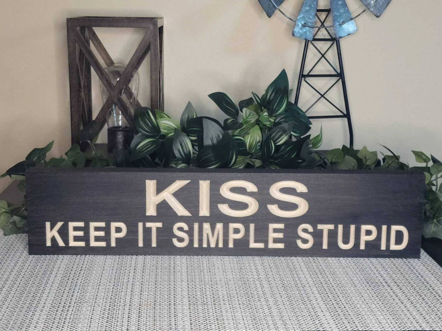 Minimalist wall art featuring a wooden motivational quote sign.
