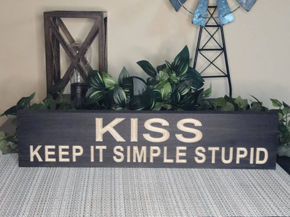 Minimalist wall art featuring a wooden motivational quote sign.
