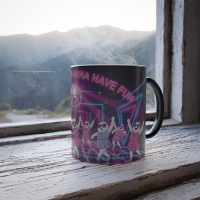 Mug with a colorful design and text 'ghouls just wANNA HAVE FUN' on a wooden surface with a window view of mountains.