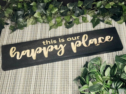 Rustic "This is Our Happy Place" wooden sign displayed in a cozy farmhouse living room.
