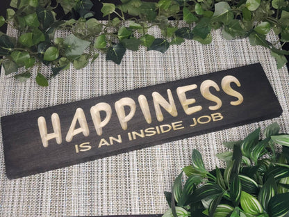 Rustic wooden "Happiness is an Inside Job" sign displayed in a cozy living room.
