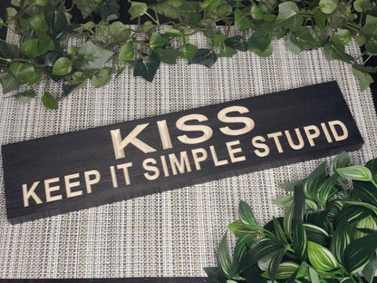 Rustic wooden "K.I.S.S. Keep It Simple Stupid" sign displayed in a home office.
