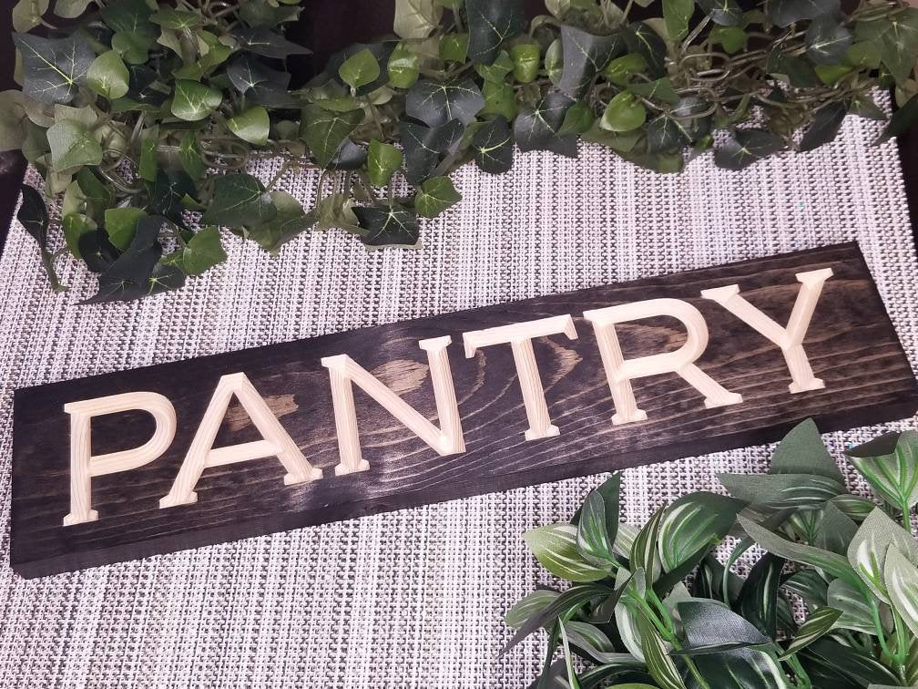 Rustic wooden "PANTRY" sign displayed on a farmhouse pantry door.
