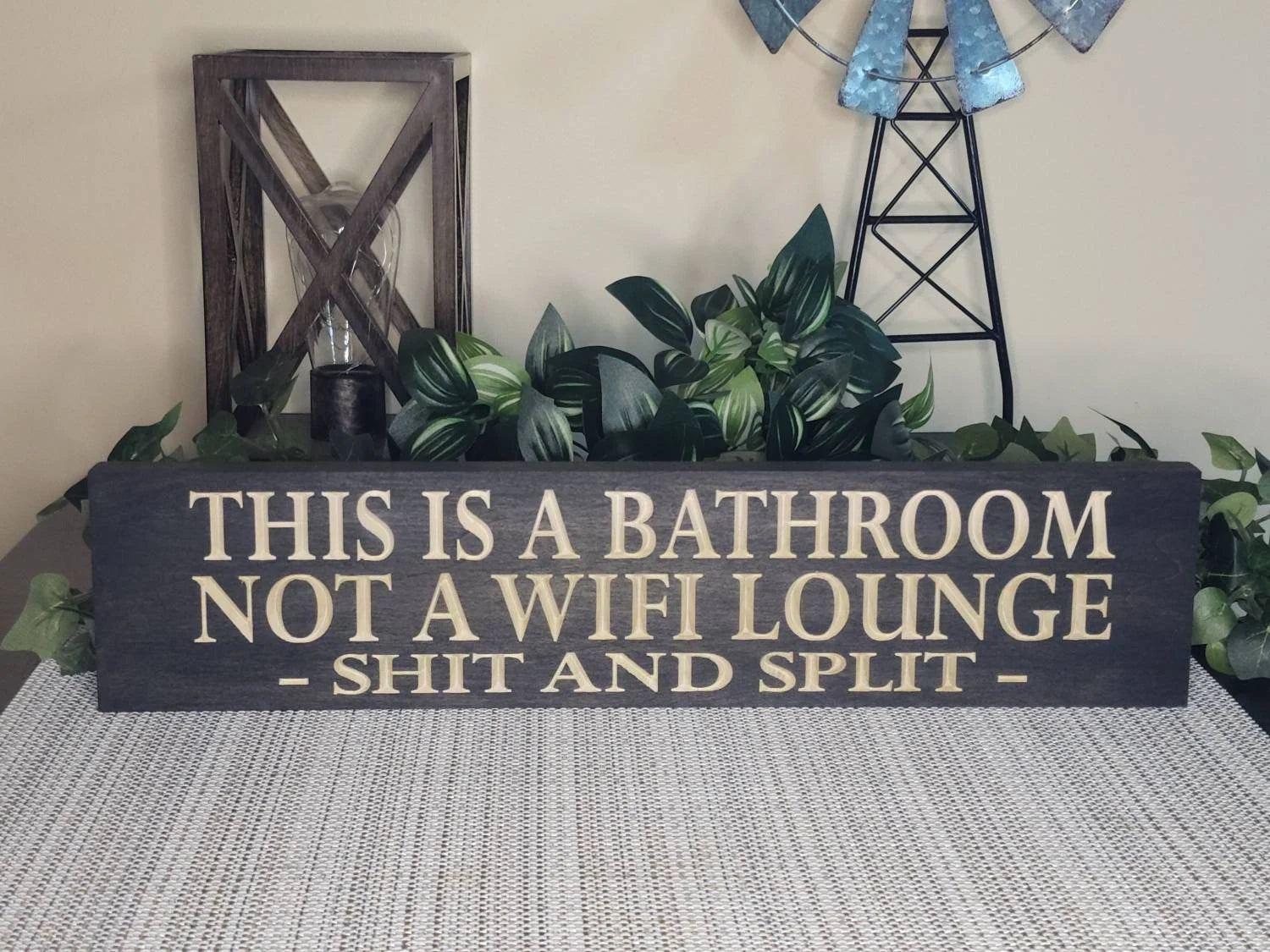 Rustic wooden bathroom humor sign displayed in a farmhouse-style powder room.
