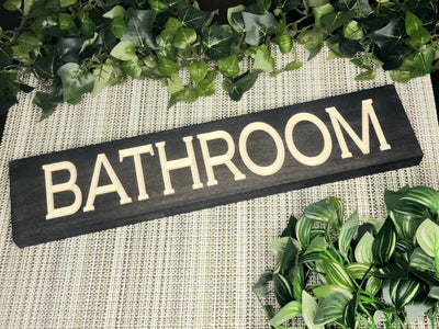 Rustic wooden bathroom sign mounted on a farmhouse-style bathroom door.
